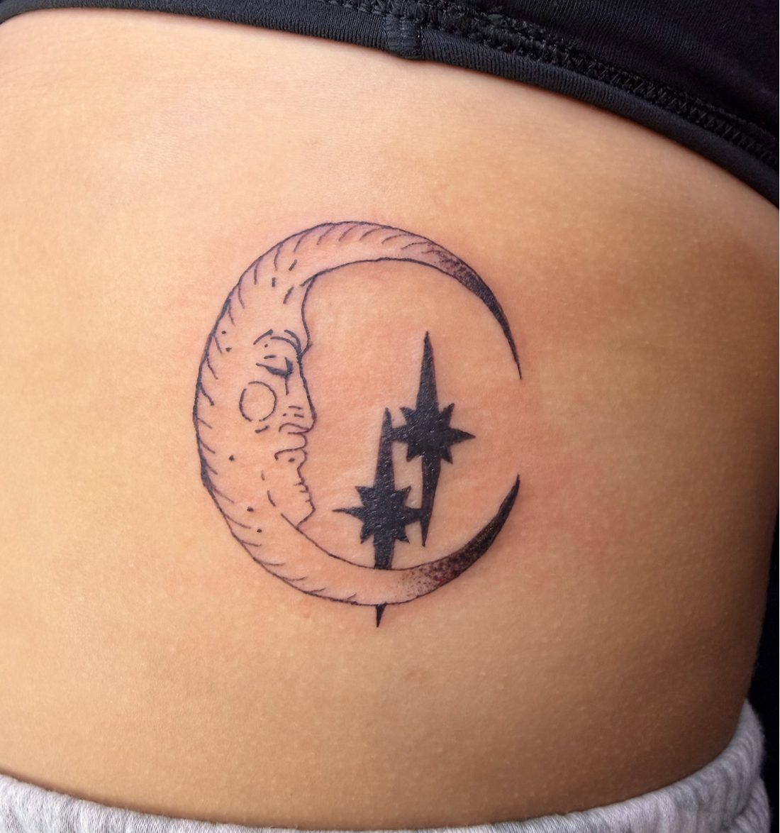 Crescent moon with a face and stars tattoo